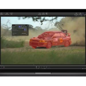 A laptop screen displays Apple Creator Studio video editing software, highlighting a rally car in red with a selection tool. The car speeds along a dirt road, kicking up dust, with trees and grass in the background.