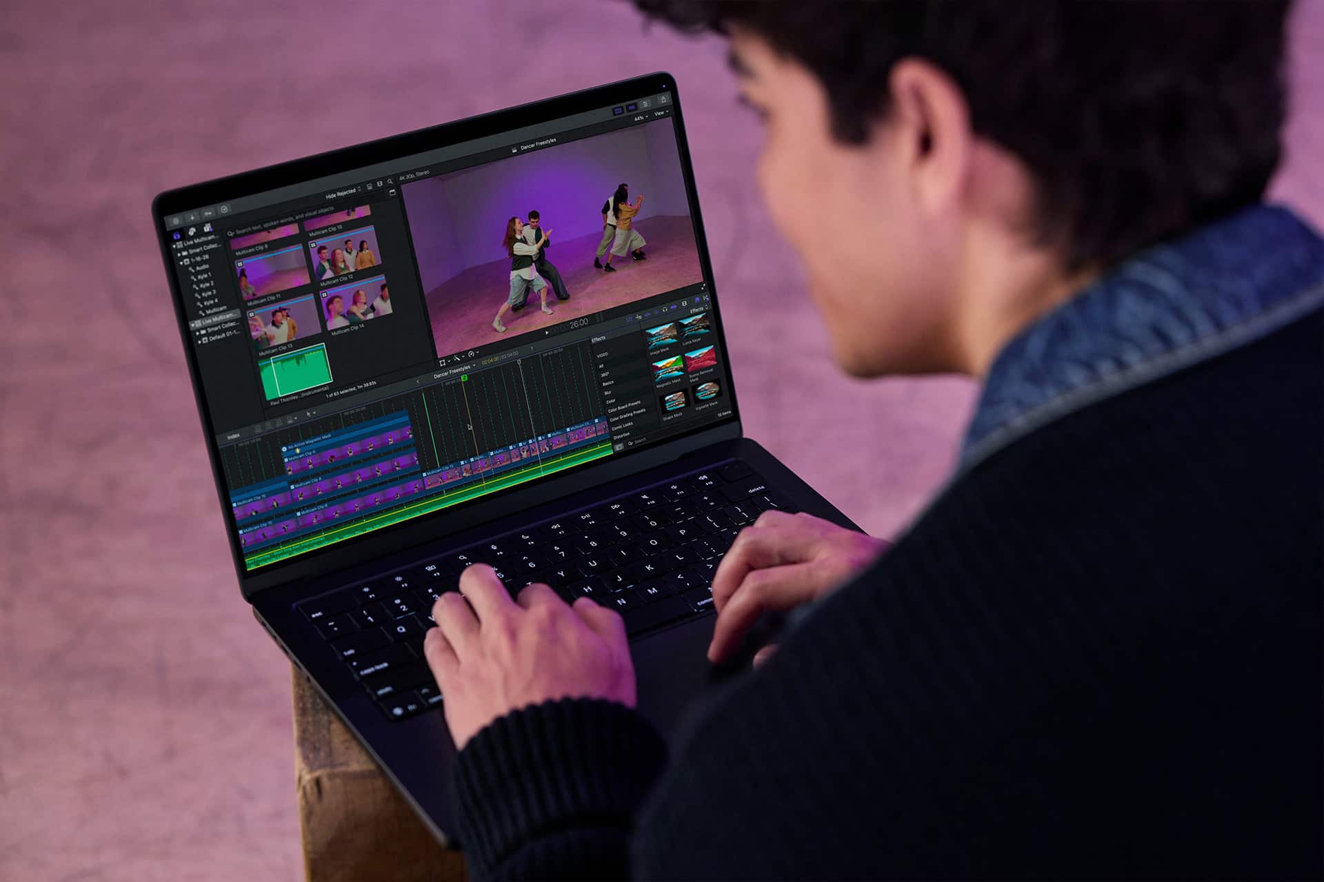 A person sits at a desk using a laptop with Final Cut Pro open, displaying various video clips and timelines on the screen.