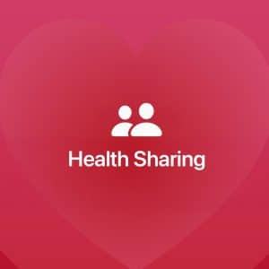 White "Health Sharing" text with two user icons above it is centered on a red-pink background with a large faint heart shape. An Apple logo appears in the bottom right corner, highlighting iPhone emergency contacts integration.
