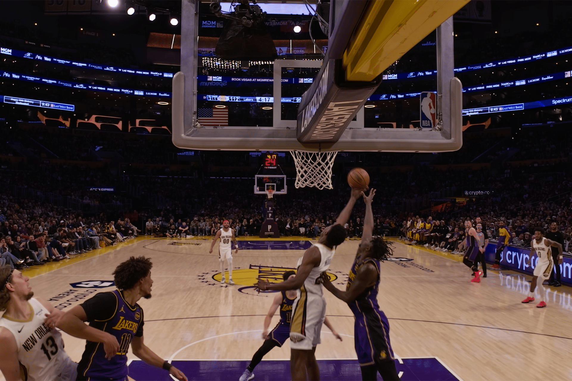 A basketball player in a white jersey jumps to block a layup attempt by a Lakers player in a purple jersey under the hoop, thrilling the crowd in a large, brightly lit arena—a true Vision Pro courtside moment.