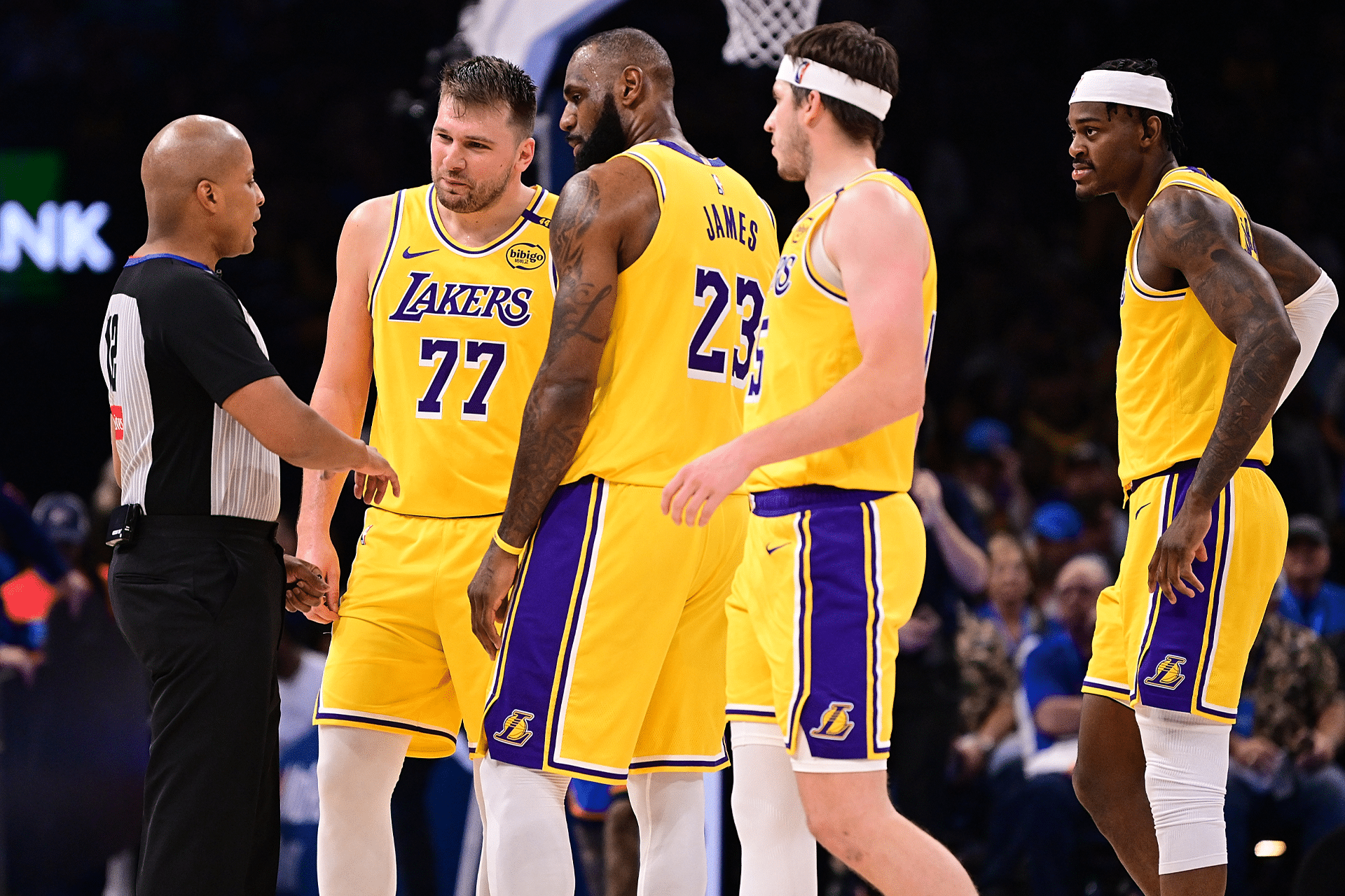 Four Los Angeles Lakers players in yellow uniforms gather around a referee on the basketball court during a Vision Pro NBA game, appearing to discuss a call. The crowd is visible in the background.