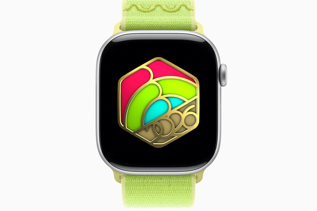 An Apple Watch with a yellow-green band displays a colorful hexagonal design featuring gold, pink, red, and green elements, with "2026" in gold at the bottom center—perfect for fitness motivation and style.