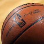 Close-up of an official NBA basketball, featuring the NBA logo, commissioner’s signature, and its textured surface on a hardwood court—perfect for streaming with Apple TV NBA League Pass.
