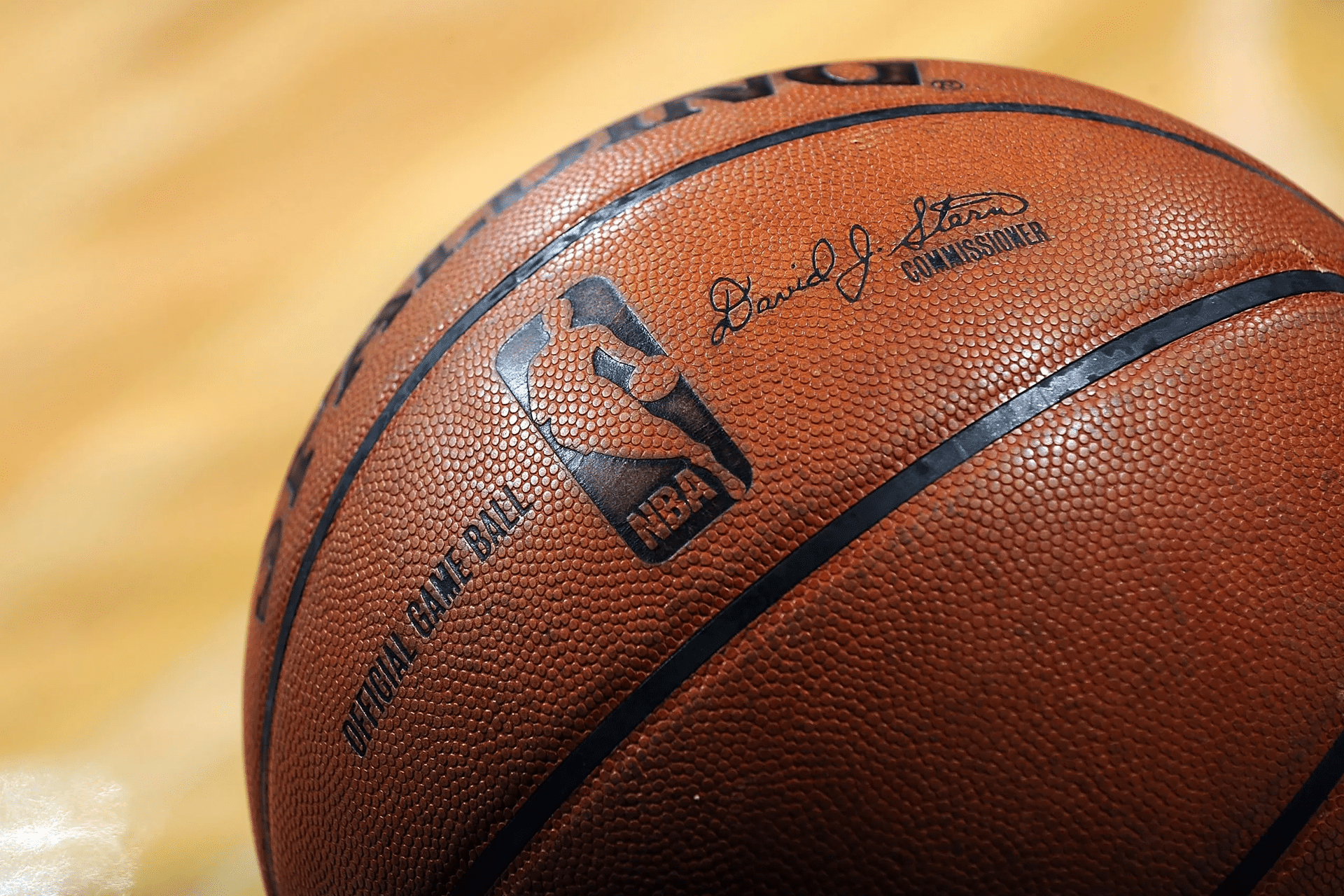 Close-up of an official NBA basketball, featuring the NBA logo, commissioner’s signature, and its textured surface on a hardwood court—perfect for streaming with Apple TV NBA League Pass.