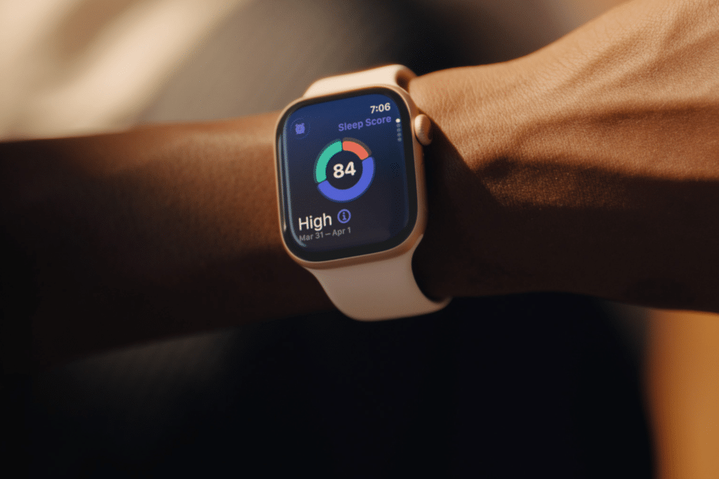 A close-up of a person’s wrist wearing a smartwatch with a light-colored band displays a sleep score of 84 marked "High" and a vibrant circular graph, highlighting the importance of apple watch screen care for clear, accurate readings.