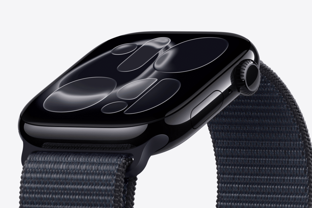 A close-up of a black smartwatch with a dark reflective screen displaying abstract, circular patterns, attached to a textured dark fabric strap, shown against a plain light background—perfect for showcasing Apple Watch screen care.