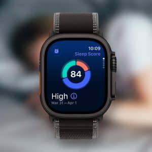 A close-up of an Apple Watch sleep screen displays a score of 84, labeled "High," with a blurred background showing a person resting in bed. - Sleep With Apple Watch