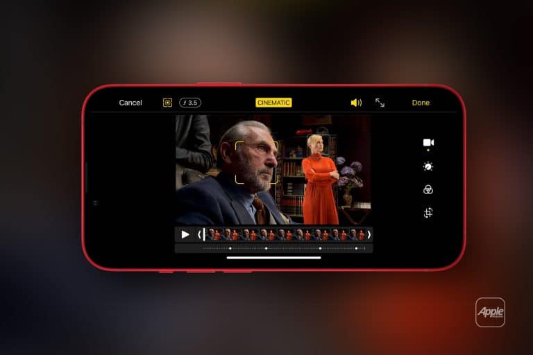 A smartphone screen displays a video editing app in iPhone Cinematic Mode, focusing on a man in a suit in the foreground and a woman in an orange outfit standing before bookshelves in the background.