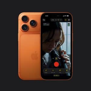 An orange iPhone with an aluminium frame and three rear cameras is shown, its screen displaying a video recording interface capturing a close-up of a person playing a cello against a dark background.