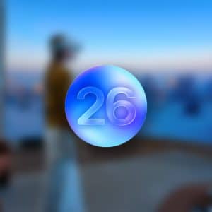A metallic blue-purple circle with the number "26" is centered over a blurred background of a person wearing a headset in a modern, brightly lit room, subtly referencing visionOS 26 Beta. The Apple logo is faintly visible in the corner.