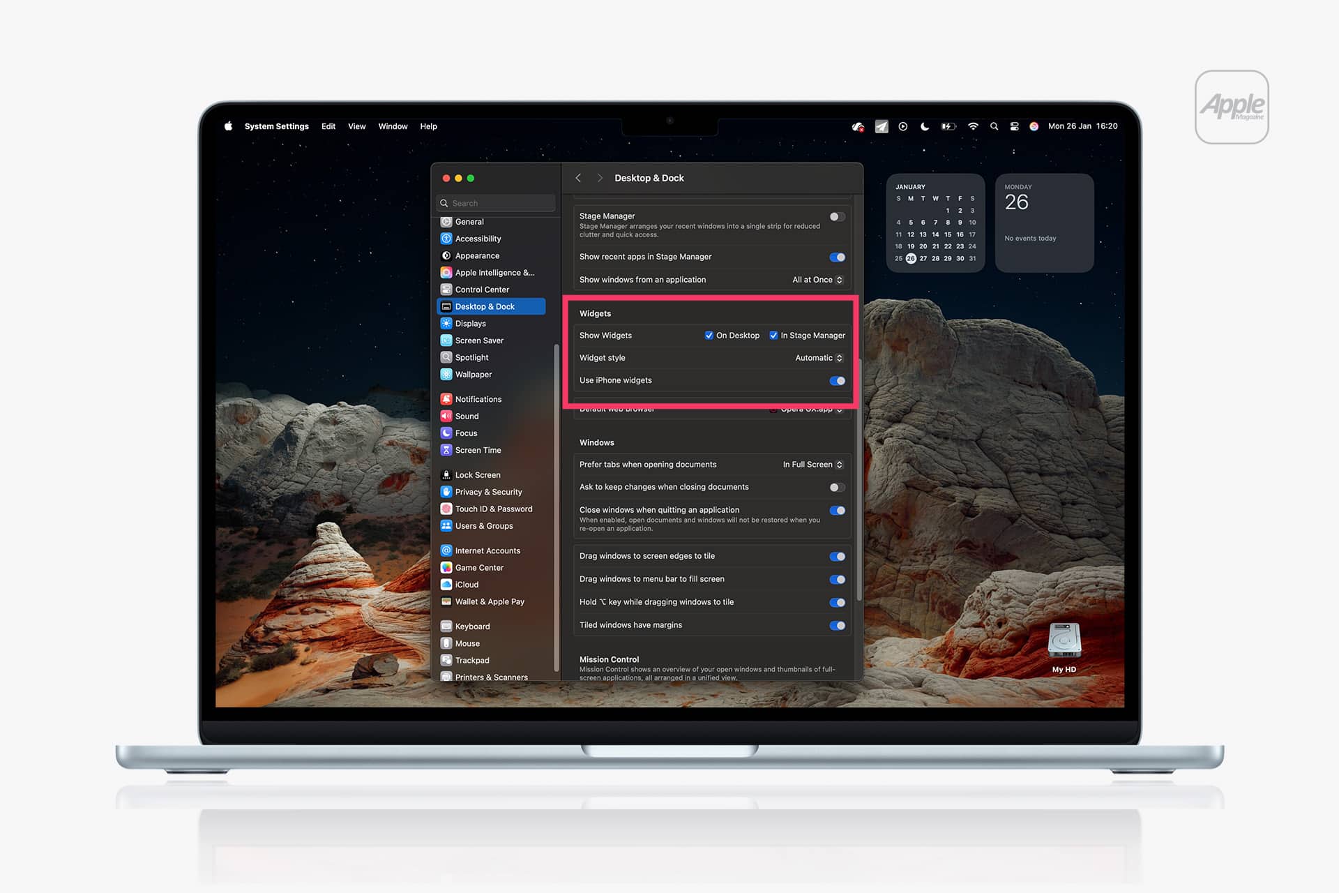 A MacBook displays the System Settings window open to “Desktop & Dock” options, featuring a desert landscape wallpaper and Mac Widgets like a calendar showing Tuesday, March 26.
