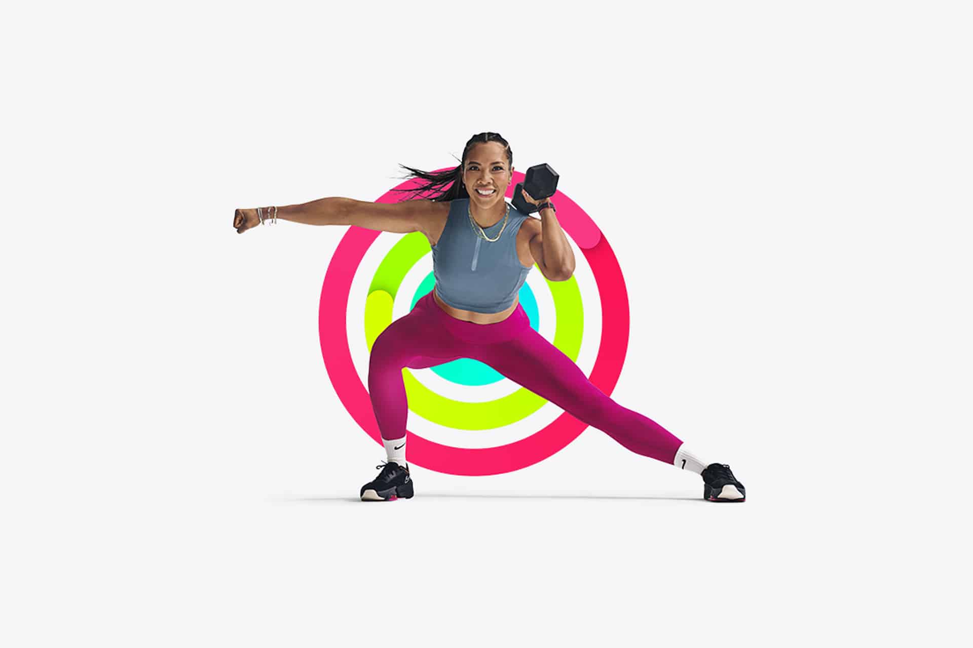 A woman in athletic wear lunges sideways while smiling, holding a dumbbell in one hand. Colorful concentric rings behind her echo the vibrant motivation of Apple Fitness Sharing, set against a plain white background.