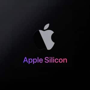 A metallic Apple logo above the words "Apple Silicon" in gradient purple and pink text on a black background, highlighting the apple silicon shift, with a small Apple logo in the bottom right corner.