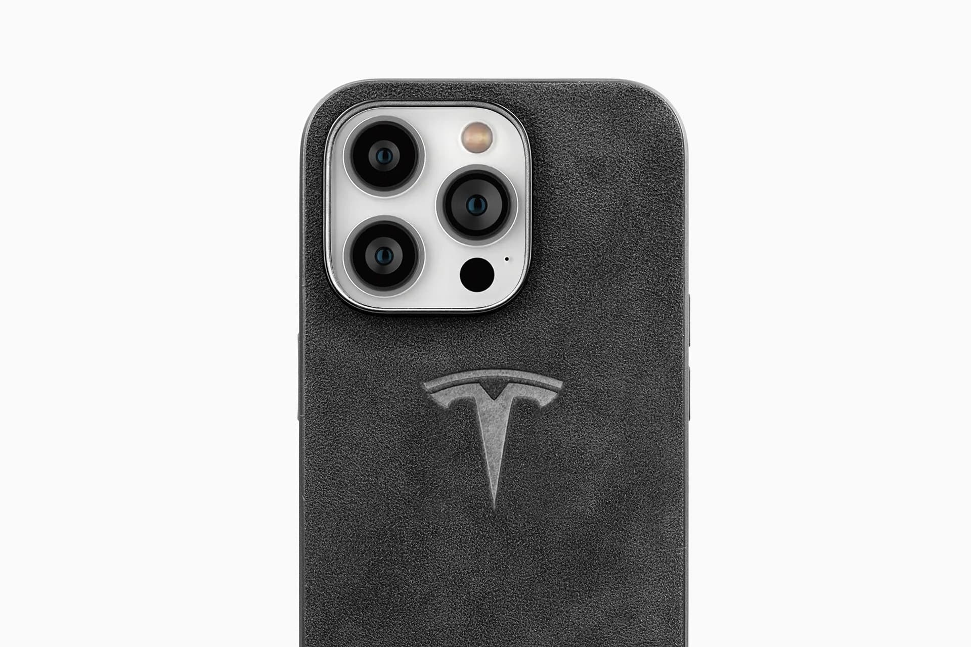 Close-up of a smartphone with a black case featuring the Tesla logo embossed below the camera lenses. Like Apple and Tesla, this design blends innovation and style. The triple camera and flash are visible at the top against a plain white background.