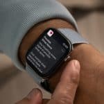 A close-up of a person’s wrist wearing a smartwatch with a light blue band, displaying a health notification about possible symptoms of atrial fibrillation and sleep data, highlighting apple accessibility features for Older Adults.