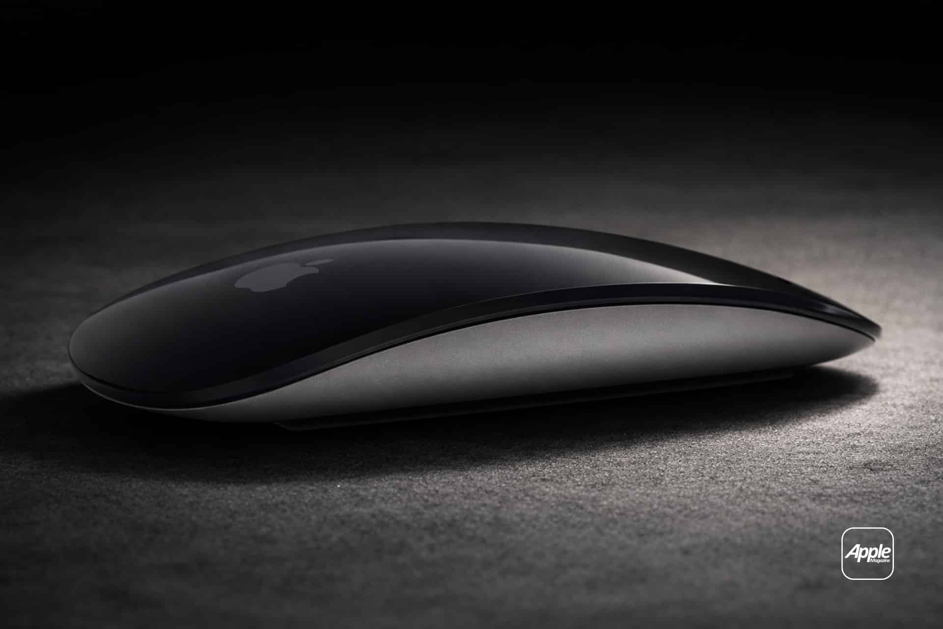 A sleek, black Apple Magic Mouse rests on a dark surface, illuminated by soft lighting. The Apple logo is visible on the mouse, highlighting its intuitive Magic Mouse Gestures. An Apple-branded badge appears in the lower right corner.