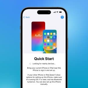 An iPhone displays the “Quick Start” setup screen, featuring two iPhones and instructions for secure transfers using Device-to-Device Data Migration, all set against a blue gradient background with a small Apple logo in the bottom right corner.