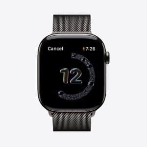 A black Apple Watch with a metallic mesh band features a colorful number "12," a circular Handwashing Timer graphic, the time 7:26, and a "Cancel" option. The Apple logo appears in the bottom right corner.