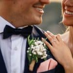 Close-up of engaged couple smiling with engagement ring visible during wedding celebration.