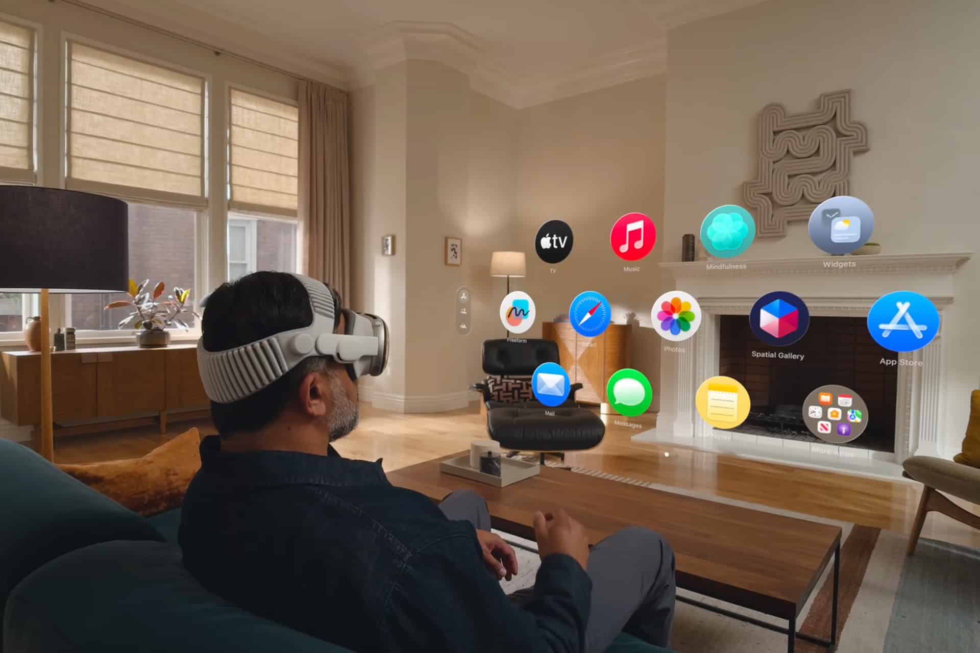 A person wearing a VR headset sits on a couch in a modern living room, seamlessly interacting with floating app icons—embracing the possibilities of the Spatial Computing Era through augmented reality before them.