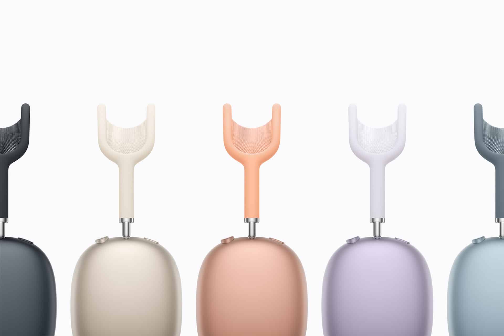 A row of five modern, minimalist wireless headphones in different pastel colors, each standing upright with ear cups facing forward against a plain, light background.