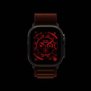 A smart watch with a dark case and brown band displays a red digital interface featuring various circular dials and numbers, all set against a black background—reminiscent of the Apple Watch Night Mode for low-light visibility.