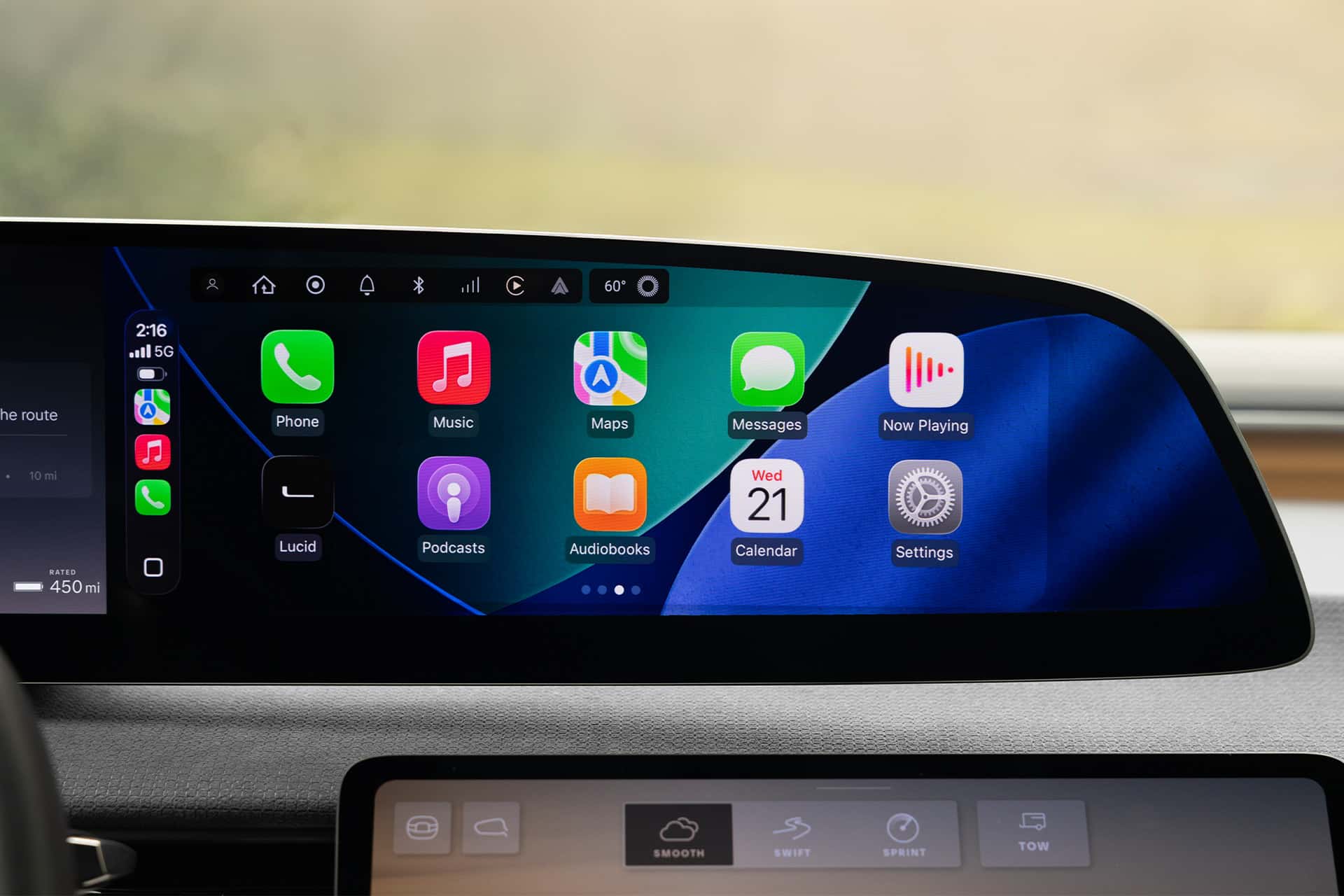 A Lucid Gravity CarPlay dashboard display shows various app icons—Phone, Music, Maps, Messages, Now Playing, Podcasts, Audiobooks, Calendar, and Settings—with a digital clock and route information conveniently on the side.