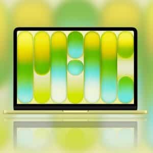 A yellow Apple laptop is open, displaying a MacBook Neo wallpaper with abstract rounded vertical shapes in yellow, green, and blue tones. The blurred background echoes these colors, with a small Apple logo in the lower right corner.