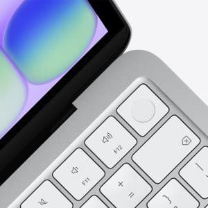 Close-up of a laptop keyboard and part of the display, with white keys, a circular fingerprint sensor button, and a colorful abstract pattern on the screen highlighting MacBook Neo performance.
