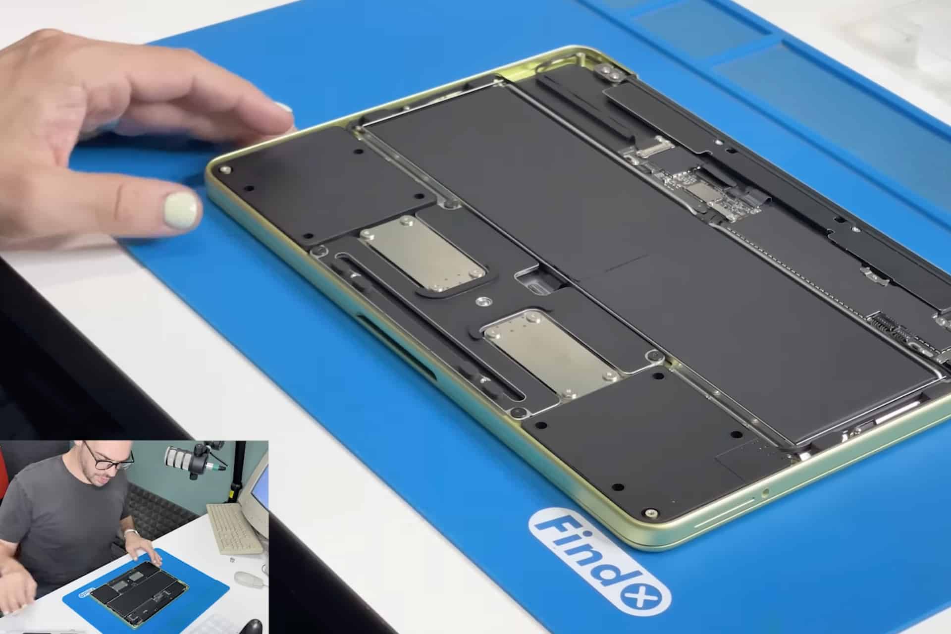 A person with painted fingernails works on an opened MacBook Neo, exposing its internal components on a blue FindX mat. An inset shows the same person talking into a microphone in front of a laptop, detailing the MacBook Neo Repair process.