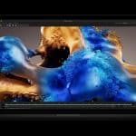 A black laptop displays a digital rendering of abstract blue and gold forms with bubble-like textures on its screen, set against a dark background.