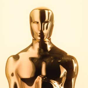 A close-up of a shiny, gold Oscar statuette against a light, neutral background, highlighting its smooth, reflective surface and stylized human form—a symbol of prestigious Apple Oscar Nominations.