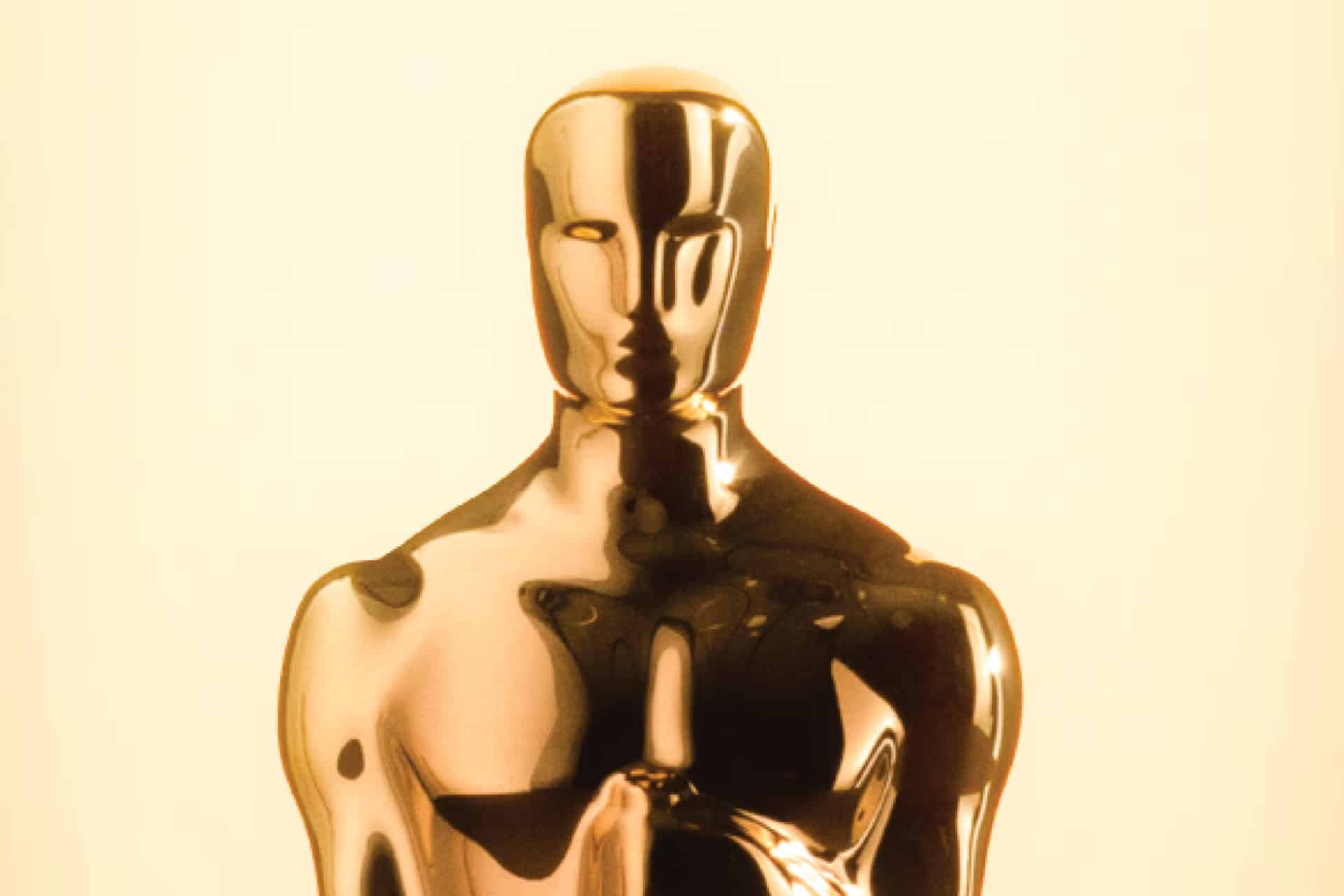 A close-up of a shiny, gold Oscar statuette against a light, neutral background, highlighting its smooth, reflective surface and stylized human form—a symbol of prestigious Apple Oscar Nominations.