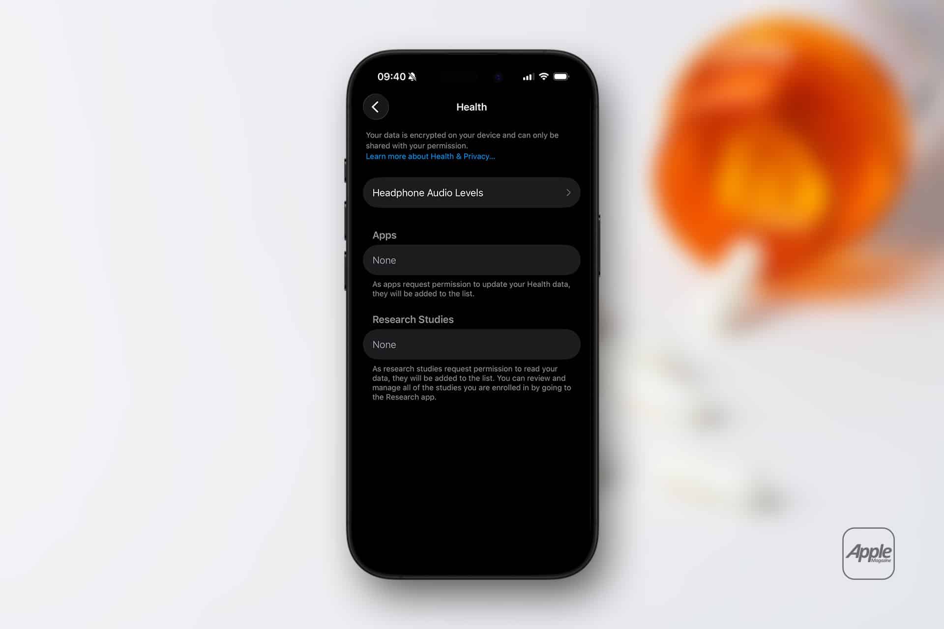 An iPhone displays the Health app screen, showing sections for Headphone Audio Levels, Apps, Medication Reminders, and Research Studies, all with no data. The background features an out-of-focus orange object and a faint Apple logo.