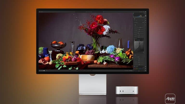 A sleek Apple monitor, tuned with Studio Display XDR settings, displays a vibrant still life of fruits, vegetables, and flowers beside a compact Apple desktop computer, all set against a gradient orange and brown background.