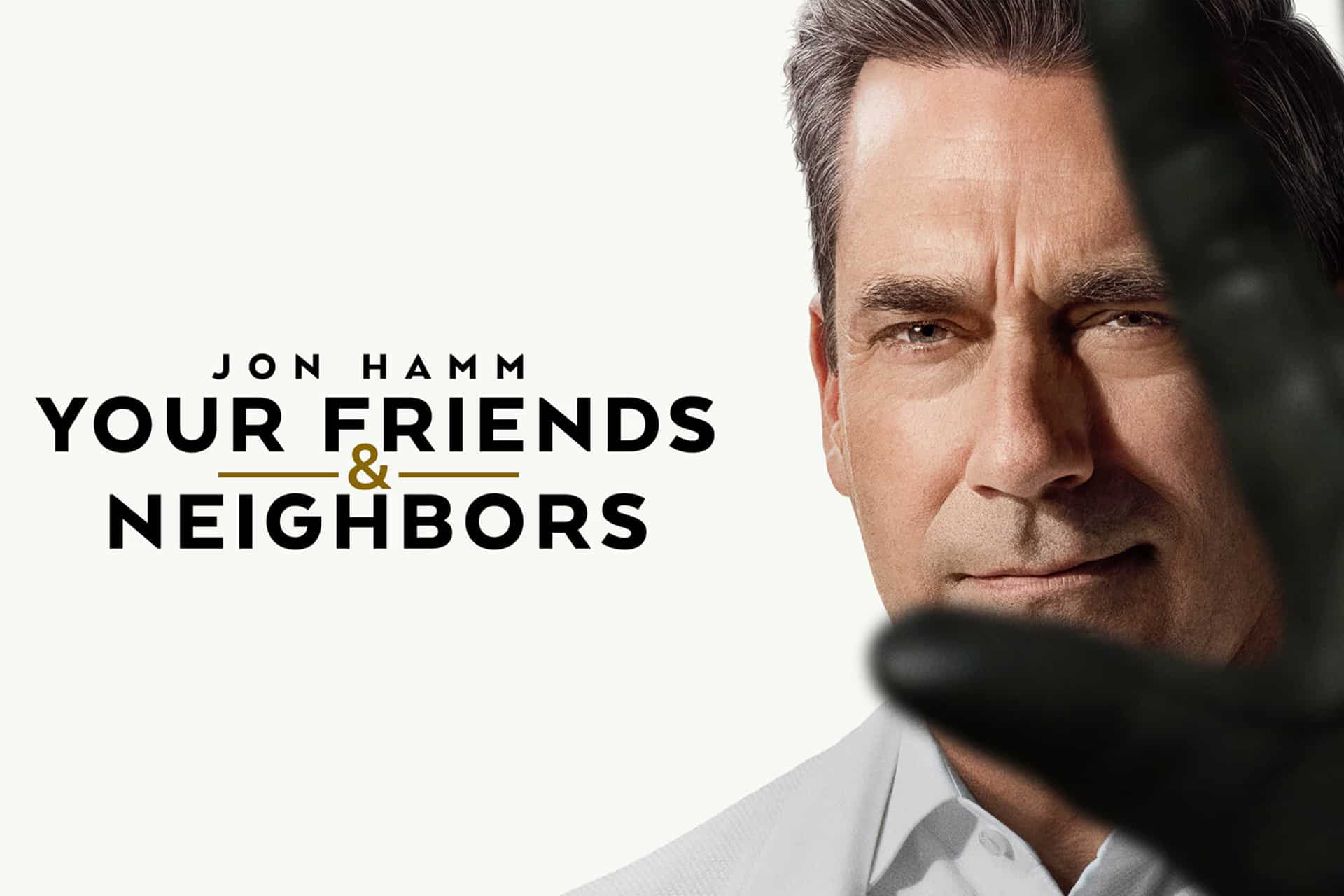 A man in a suit faces forward, partially obscured by a gloved hand. Text reads: "Jon Hamm Your Friends & Neighbors." The minimalist, white background highlights the intrigue of Your Friends & Neighbors.