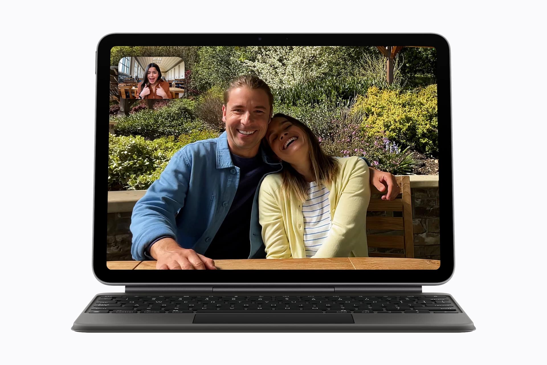 iPad Air 2026 - A tablet with a keyboard shows a video call. On the screen, a smiling couple sits together outdoors, and a woman appears in a smaller window, also smiling—highlighting the seamless connection made possible by Apple Core AI.