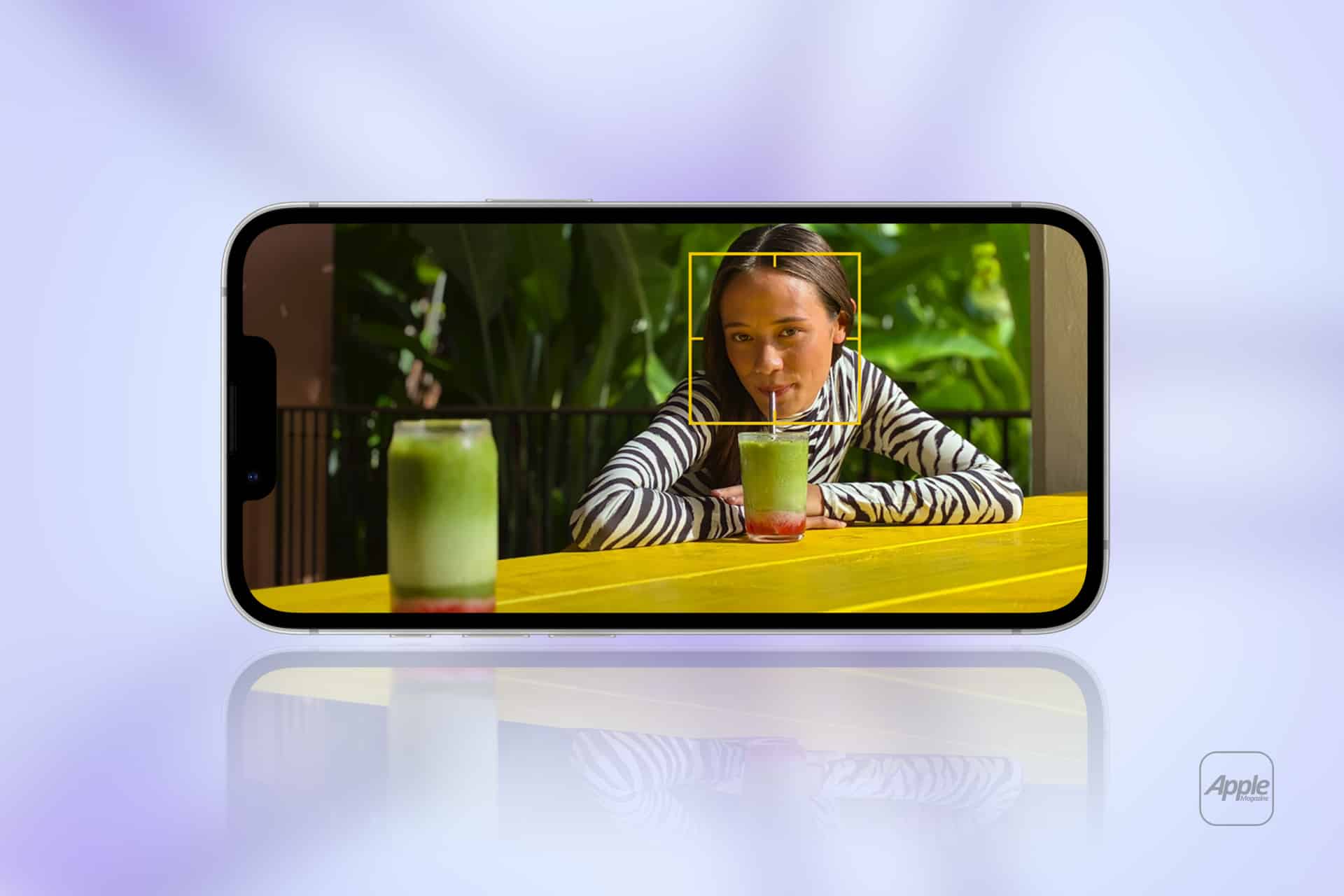 A smartphone displays a woman drinking from a glass at a yellow table with another drink; she sits in front of green plants. The reflected image shows the same scene. An Apple logo appears in the lower right corner.
