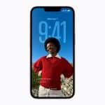 An iPhone displays its lock screen, showing the time as 9:41 and the date as Wednesday, April 1. Thanks to Apple Core AI, the background—a photo of a smiling person in a red sweater outdoors—appears sharper. Notification and focus mode icons appear below.
