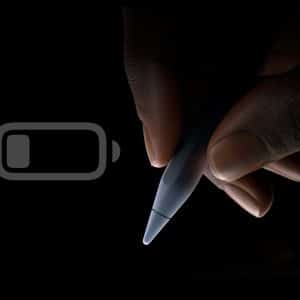 A hand holds an Apple Pencil against a black background; a dim battery icon—hinting at good Apple Pencil battery habits—appears next to it, and the Apple logo is visible in the lower right corner.