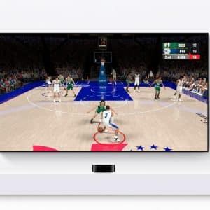 A TV mounted on a white wall shows a basketball video game as part of an Apple TV gaming setup, with a player in white dribbling toward the basket against green and the scoreboard reading BOS 12, PHI 16, 2nd quarter, 4:48 left.