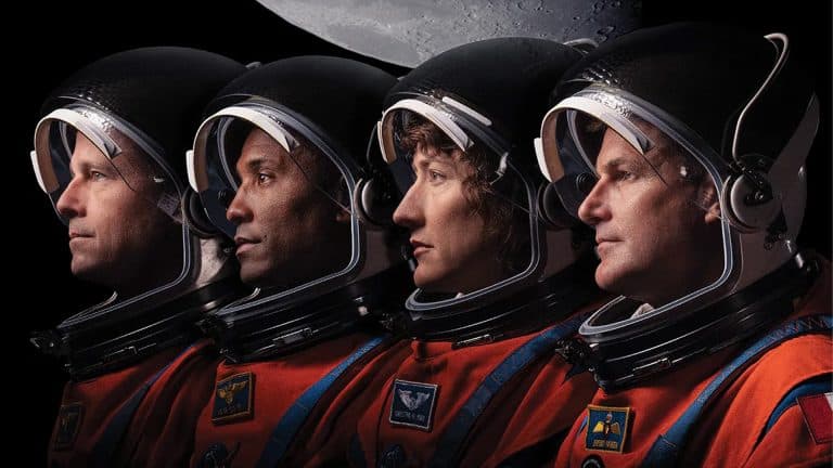 Four Artemis II astronauts wearing orange spacesuits and black helmets are shown in profile, looking to the right, with the gray surface of the Moon above them against a black background—ready for their mission as iPhones capture every moment.