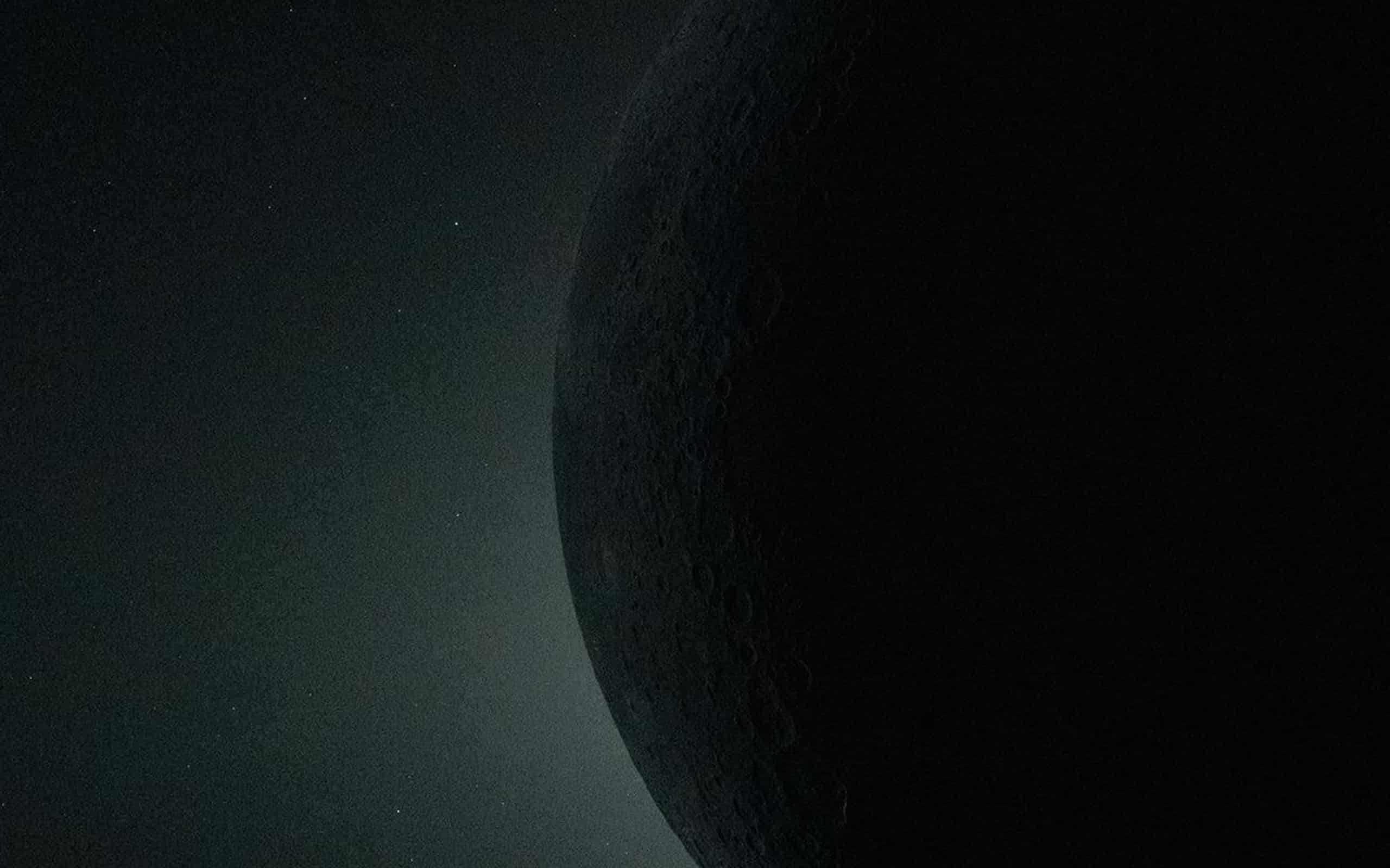 A dark, shadowed planet or moon with a cratered surface is partially illuminated on the right, set against a faintly glowing star field in space—its details rendered with lifelike clarity reminiscent of Apple GPU memory precision.