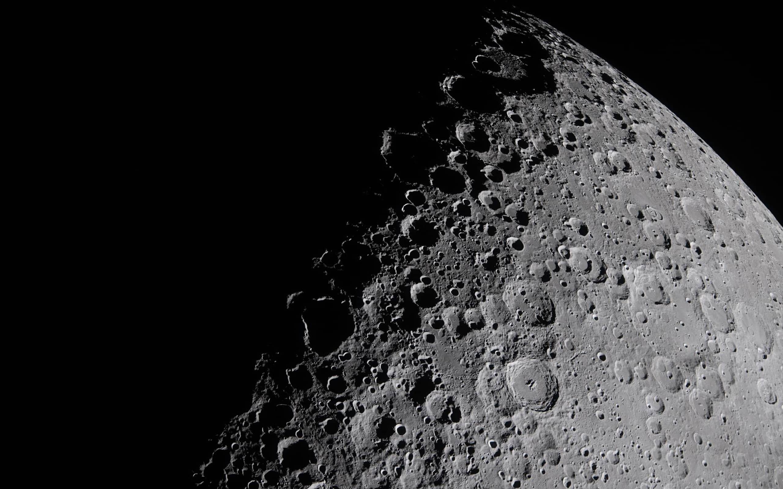 A close-up view of the Moon’s surface, showing numerous craters and rugged terrain, is rendered with vivid detail—highlighting the contrast between light and shadow, as if processed by advanced Apple GPU memory against the blackness of space.