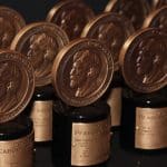 Rows of Peabody Awards from the 86th Annual Peabody Awards, featuring bronze medallions with a profile portrait, are displayed on black bases with gold nameplates, arranged closely together against a dark background.