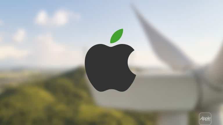 The black Apple logo with a green leaf is centered over a blurred background of a wind turbine and green hills, symbolizing Apple sustainability partners' commitment to renewable energy and environmental sustainability.