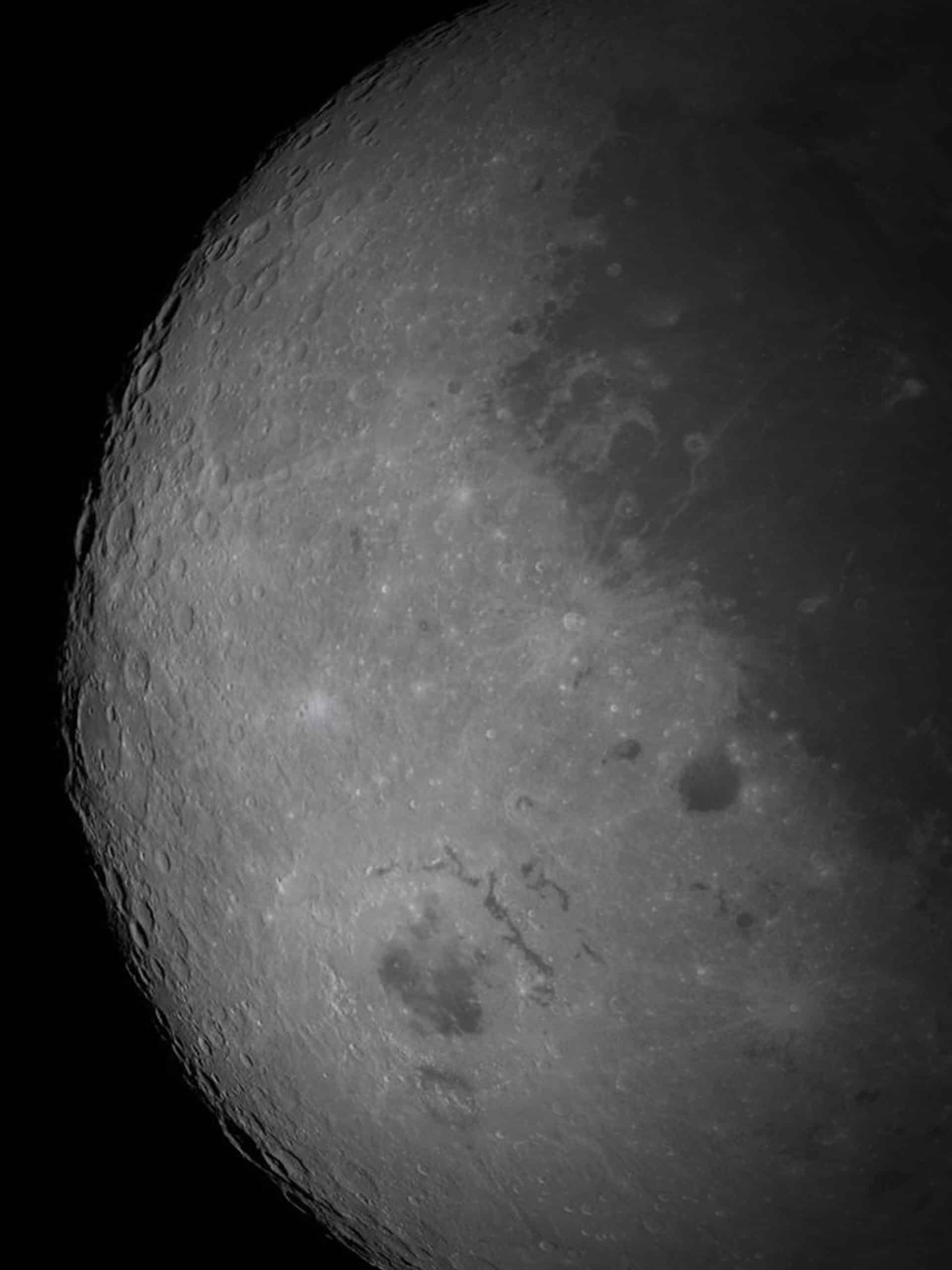 Close-up view of the moon's surface showing craters and rough terrain, with light and dark regions highlighted in detail—almost as if seen through the clarity of Apple GPU memory—against a black background.