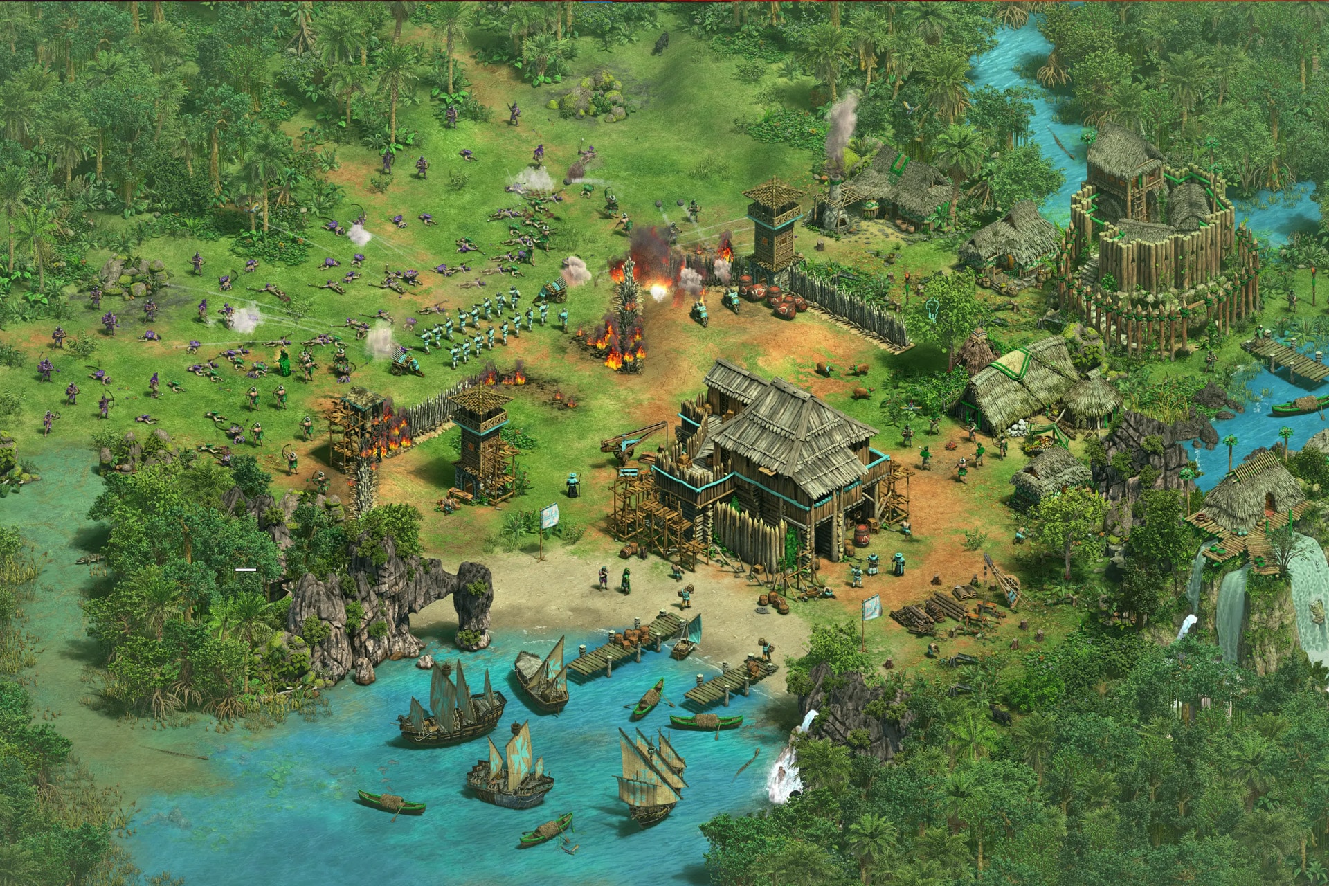 An overhead view of a riverside village under attack in a tropical setting, reminiscent of Age of Empires II Mac, features burning wooden buildings, defending soldiers, approaching boats, and dense jungle surrounding the scene.