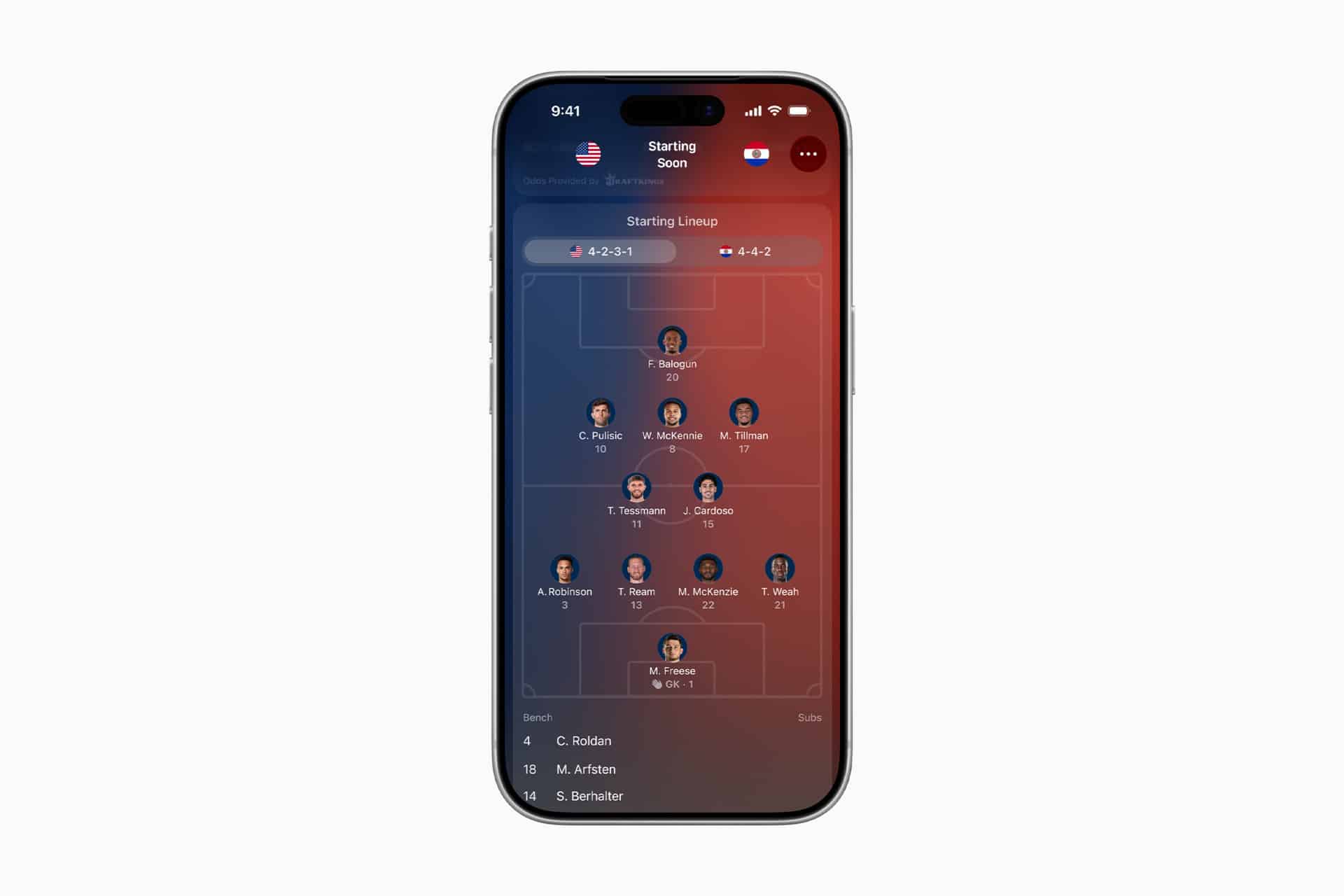 A smartphone displaying a soccer lineup for a team in a 4-3-3 formation, with player photos and names on a digital field. The red-blue background adds flair, while Apple Sports Live Activities keep fans updated ahead of World Cup 2026. Bench players shown below.