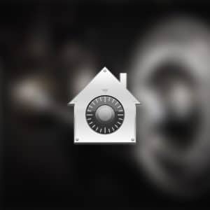 A metallic house-shaped icon with a combination lock dial in the center, symbolizing FileVault security, appears over a blurred background. The Apple logo is visible in the lower right corner.